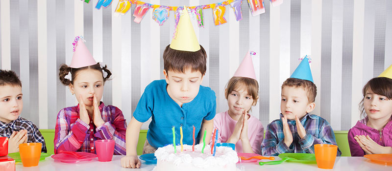Young Boy Blows Out Candles With Friends